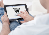 Mann beim Online-Shopping mit dem Tablet auf der Couch