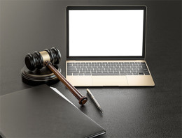 Richterhammer auf einem Tisch neben Laptop, Stift und Akte