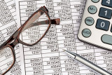 Taschenrechner, Brille und Kugelschreiber auf Finanz-Aufstellungen, Zahlen