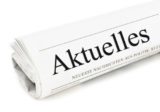 zusammengerollte zeitung auf der groß "Aktuelles" zu lesen ist