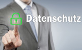 Mann im Anzug drückt mit dem Finger auf ein grünes Schloss vor dem Schriftzug "Datenschutz"