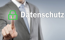 Mann im Anzug drückt mit dem Finger auf ein grünes Schloss vor dem Schriftzug "Datenschutz"