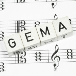 weiße Würfel mit der Aufschrift GEMA auf Musiknoten