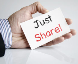 Hand hält Zettel mit Aufschrift "Just Share!"