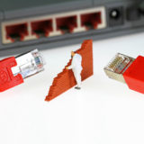 Keine Verbindung, Miniaturmensch baut Mauer zwischen 2 Lan-Kabeln und dem Ln-Anschluss eines Laptops