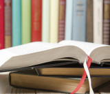 Aufgeschlagenes Buch, im Hintergrund weitere Bücher