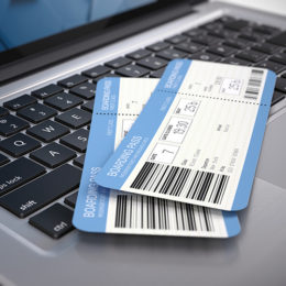 Zwei Flugtickets liegen auf der Tastatur eines Laptops