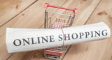 Einkaufswagen mit einer Zeitung mit der Aufschrift "Online Shopping"