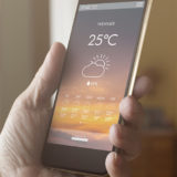 Handy in der Hand mit Wettter-App