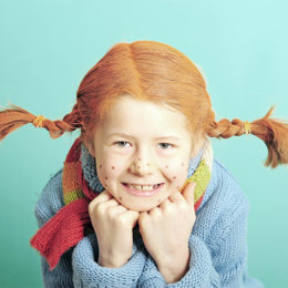 Ein als Pippi-Langstrumpf verkleidetes Mädchen stützt sich auf ihre Ellbogen ab.