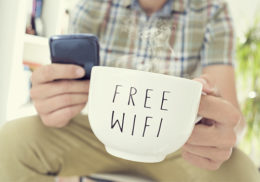 Mann hält Tasse mit der Aufschrift "Free Wifi"