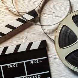 Filmklappe neben Filmrolle auf Holzboden