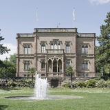 Ein großes Herrenhaus mit Springbrunnen im Garten.