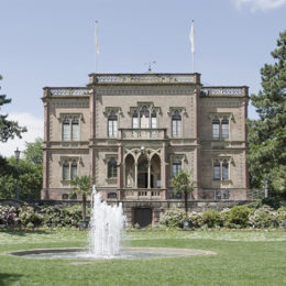 Ein großes Herrenhaus mit Springbrunnen im Garten.