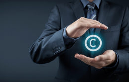 Blaues Copyright-Zeichen zwischen zwei Händen.