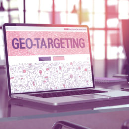 Laptopt steht in einer modernen Büro-Umgebung auf dem Schreibtisch, das Display zeigt Geo-Targeting an