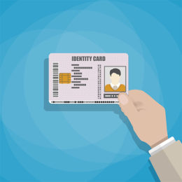 Hand hält einen Personalausweis vor blauem Hintergrund