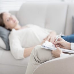 Psychologe, Therapeut spricht mit Frau auf Couch und macht Notizen