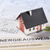 Modell eines Einfamilienhauses das auf einem Energieausweis steht