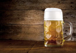 Bier in einem Maßkrug vor einem rustikalen Hintergrund