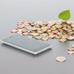 Handy liegt auf Tisch mit Münzen