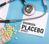 Stethoskop und Medikamente liegen auf einem hellblauen Hintergrund. Daneben liegt ein weißer Zettel mit der Aufschrift „DIAGNOSIS PLACEBO EFFECT“