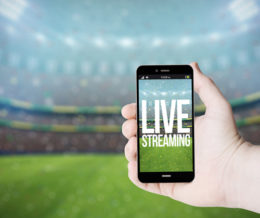 ein Handy auf dem Live Streaming steht, und der Hintergrund eines Fußballstadions ist auf dem Display zu sehen