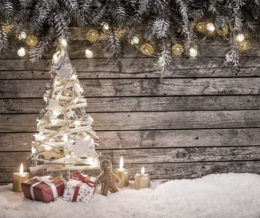 ein Weihnachtsbaum mit Geschenken vor hölzernem Hintergrund