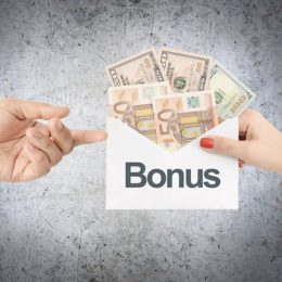 Frauenhand übergibt Männderhand einen mit Geldscheinen gefüllten Umschlag mit der Aufschrift "Bonus"