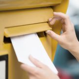 Frau wirft Brief in gelben Briefkasten ein