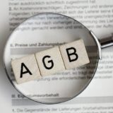 AGB-Schriftzug liegt auf einem Vertrag und werden durch eine Lupe betrachtetmit einer Lupe genauer angeschaut