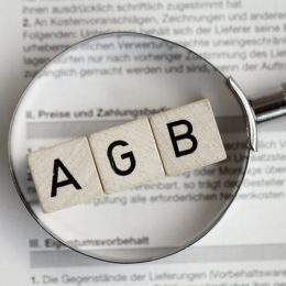 AGB-Schriftzug liegt auf einem Vertrag und werden durch eine Lupe betrachtetmit einer Lupe genauer angeschaut