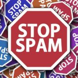 Großes rotes Schild mit Aufrschrift "Stop spam" mit vielen kleineren zum Teil andersfarbigen Schildern im Hintergrund