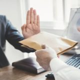 Geschäftsmann lehnt Umschlag mit Geld ab