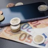 Ein Smartphone inmitten von Geldscheinen und Münzen