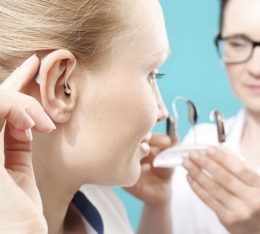 Frau testet beim Ohrenarzt verschiedene Hörgeräte aus