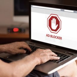 Mann sitzt vor Laptop mit Ad-Blocker auf Bildschirm