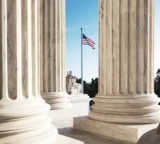 Säulen von dem Supreme Court der USA mit Flagge der Vereinigten Staaten im Hintergrund