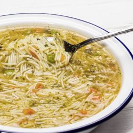 Fertigsuppe auf Emaille Teller auf Holz Hintergrund mit Löffel