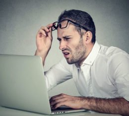 Mann schaut ungläubig und verständnislos auf Bildschirm