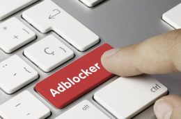 Finger drückt auf rote Adblock-Taste auf einer Tastatur