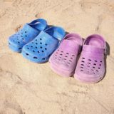 Crocs in rosa und blau im Sand