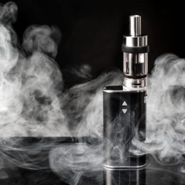 E-Zigarette auf einem schwarzen Tisch mit Dampf umgeben