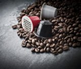 Kaffeekapseln in den Farben rot, grau und schwarz auf Kaffeebohnen