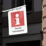 weißes und rotes Tourist Information Schild hängt vor einem Gebäude