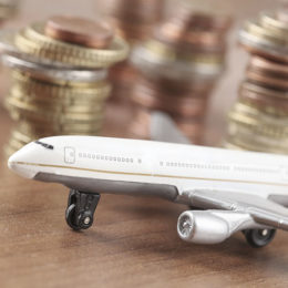 Kleines Flugzeug mit Münzen im Hintergrund