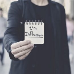 Person hält Block mit der Aufschrift "I'm Influencer" vor sich
