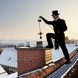 Schornsteinfeger bei der Arbeit im Winter auf dem Dach eines Hauses