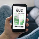 Frau hält Smartphone in der Hand und bucht Online-Tickets