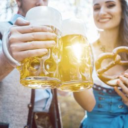 Pärchen in bayerischer Tracht prostet sich mit Bierkrügen zu